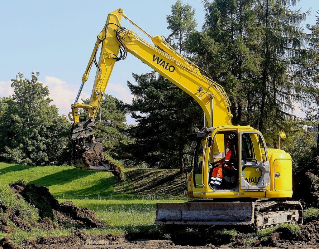 Excavator digging soil in a construction site, highlighting heavy machinery used for land clearing and demolition services.